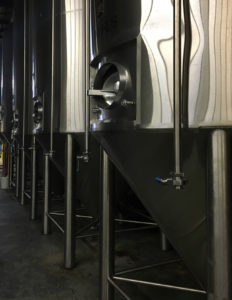 a row of beer fermenters at peabody heights brewery in baltimore, maryland, photographed by jamie bannon photography.