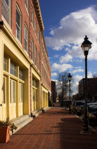 yellow doors line the brick sidewalk in the fell's point neighborhood of baltimore, maryland, photographed by jamie bannon photography.