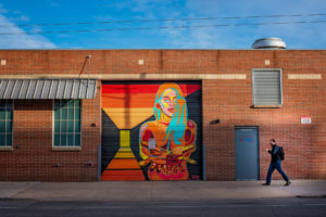a man walks past a garage door with street art in the rino art district of denver, colorado, photographed by jamie bannon photography.