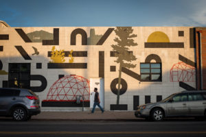 a man walks past a building with street art in the rino art district of denver, colorado, photographed by jamie bannon photography.