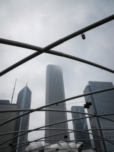downtown chicago buildings in the fog, viewed through the jay pritzker pavilion at millennium park, photographed by jamie bannon photography.