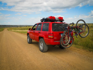 red jeep grand cherokee parked on a dirt road in badlands national park, south dakota, photographed by jamie bannon photography.