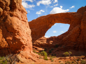 a large arch in the red rocks of moab, utah, photographed by jamie bannon photography.
