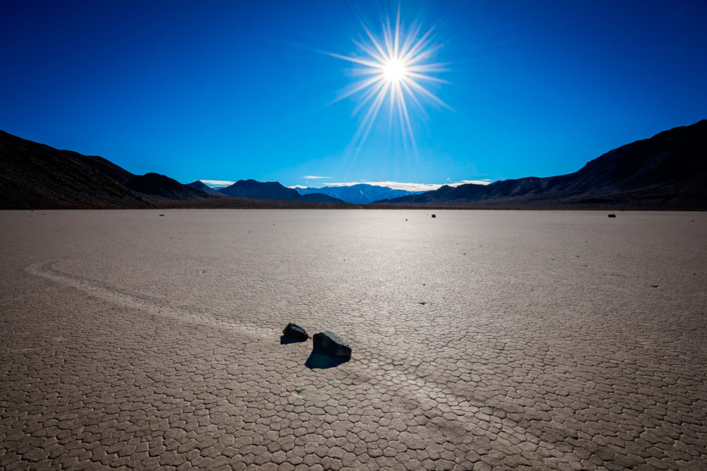two sliding rocks in line to collide on the racetrack playa in death valley, california, photographed by jamie bannon photography.