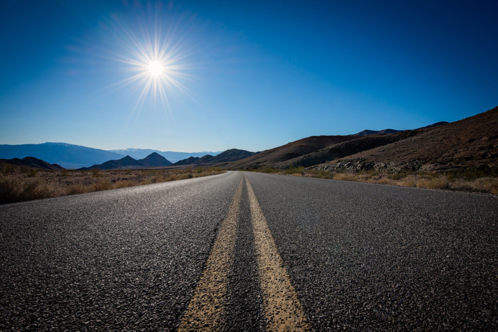 road with sun in death valley, california, photographed by jamie bannon photography.
