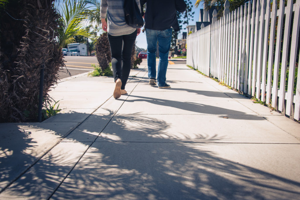 a man and a woman walk down the street in san diego, california, photographed by jamie bannon photography.
