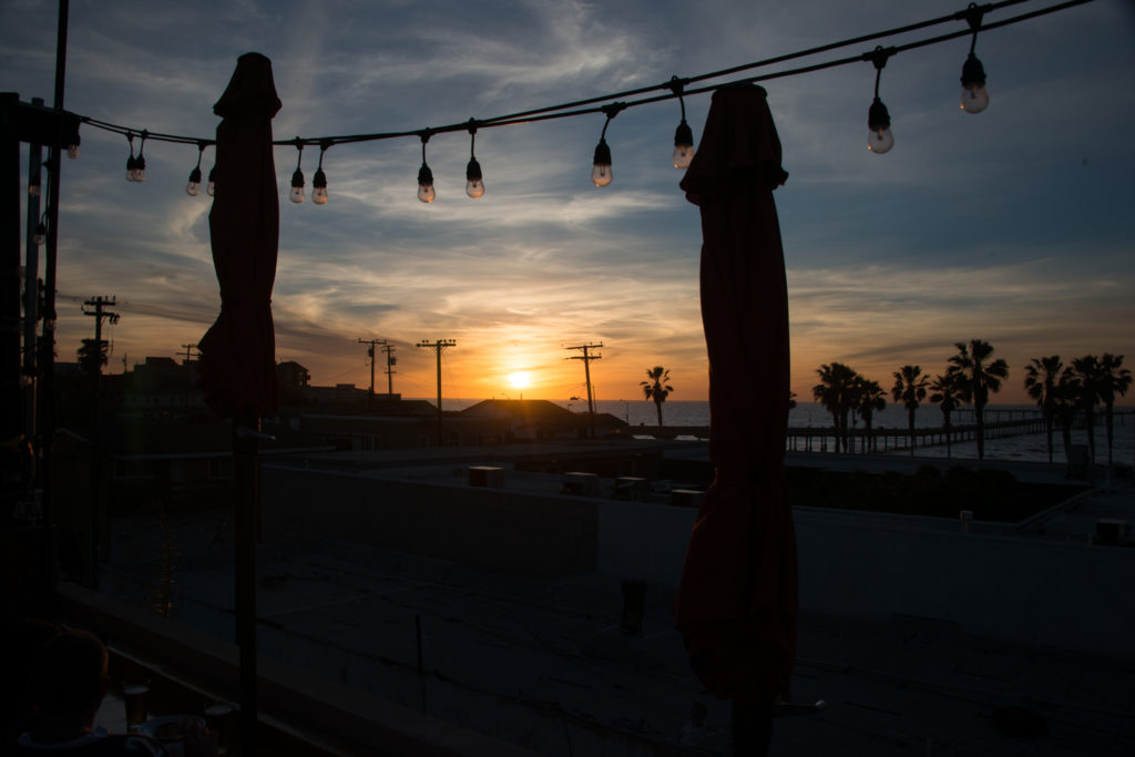 the sun sets over ocean beach at ob brewery in san diego, california, photographed by jamie bannon photography.
