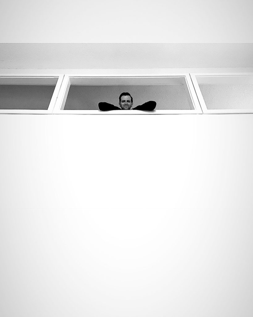 man looks over from the second floor through a window, photographed by jamie bannon photography.