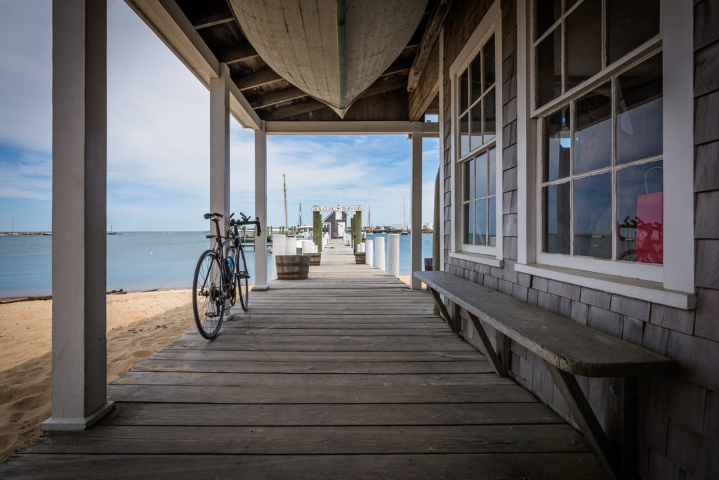 a bicycle leans against the pier at the black dog wharf and marina on martha's vineyard, photographed by jamie bannon photography.