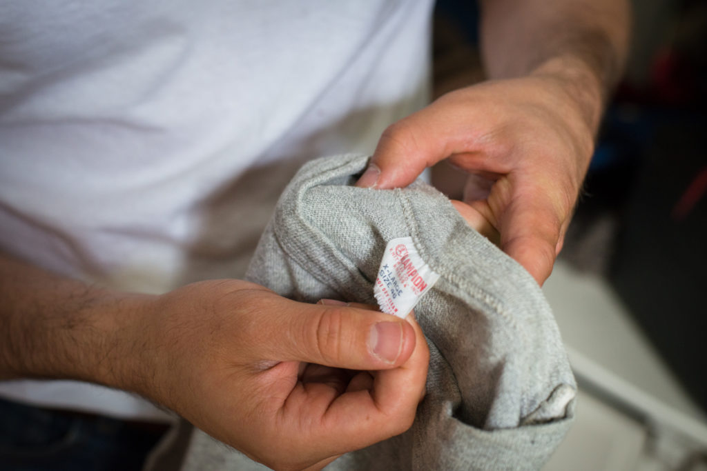 michael pontacoloni, the owner of comma, vintage menswear subscription service, inspects the tag on a t-shirt, photographed by jamie bannon photography
