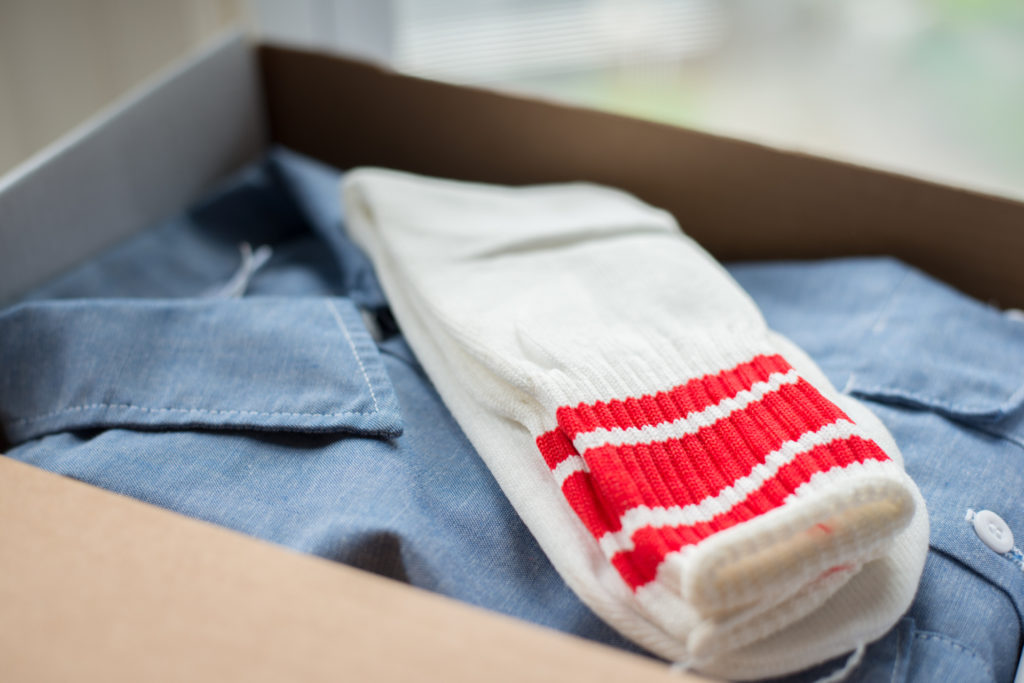 box with dickies button-down shirt and white and red striped tube socks as part of a comma, vintage menswear subscription box, taken for a brand shoot by jamie bannon photography.