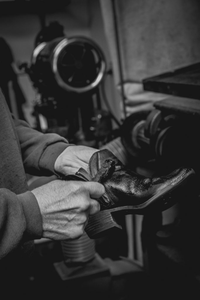 black and white close-up of a cobbler's hands working in his shoe repair shop in unionville, connecticut, photographed by jamie bannon photography.