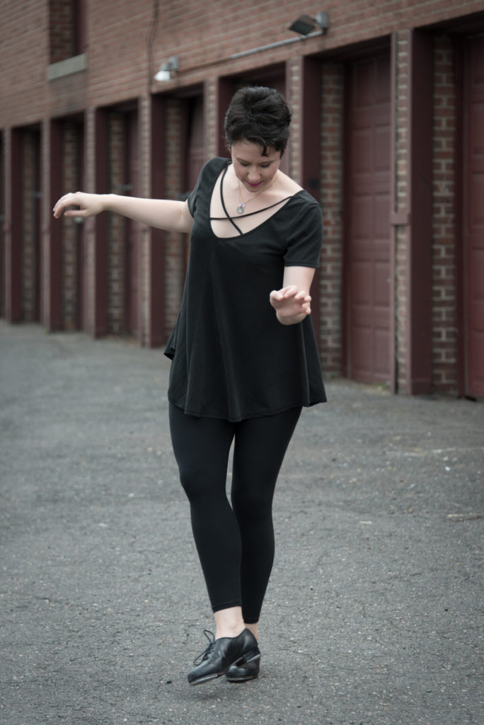 a woman tap dances outside in front of a row of garages, in west hartford, connecticut, photographed by jamie bannon photography.