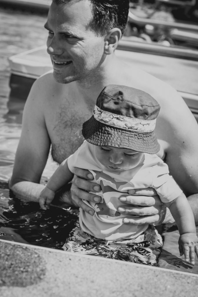 black and white image of a dad taking his baby swimming for the first time, photographed by jamie bannon photography.