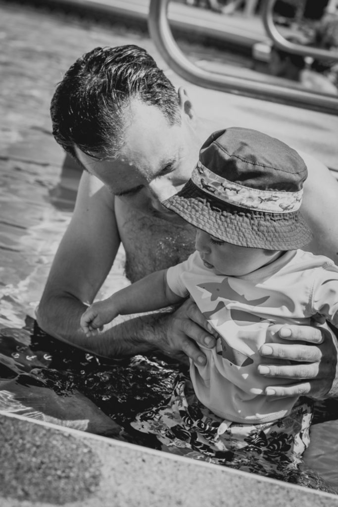 black and white image of a dad taking his baby swimming for the first time, photographed by jamie bannon photography.