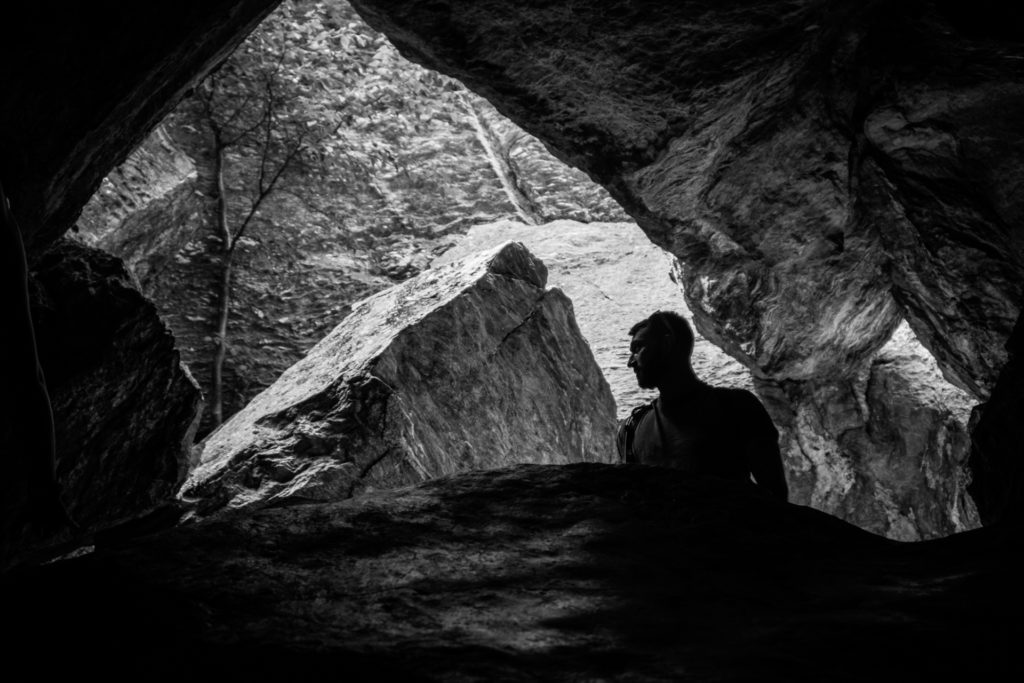a man pauses under geometric shapes formed by rocks at smugglers' notch state park in vermont, photographed by jamie bannon photography.
