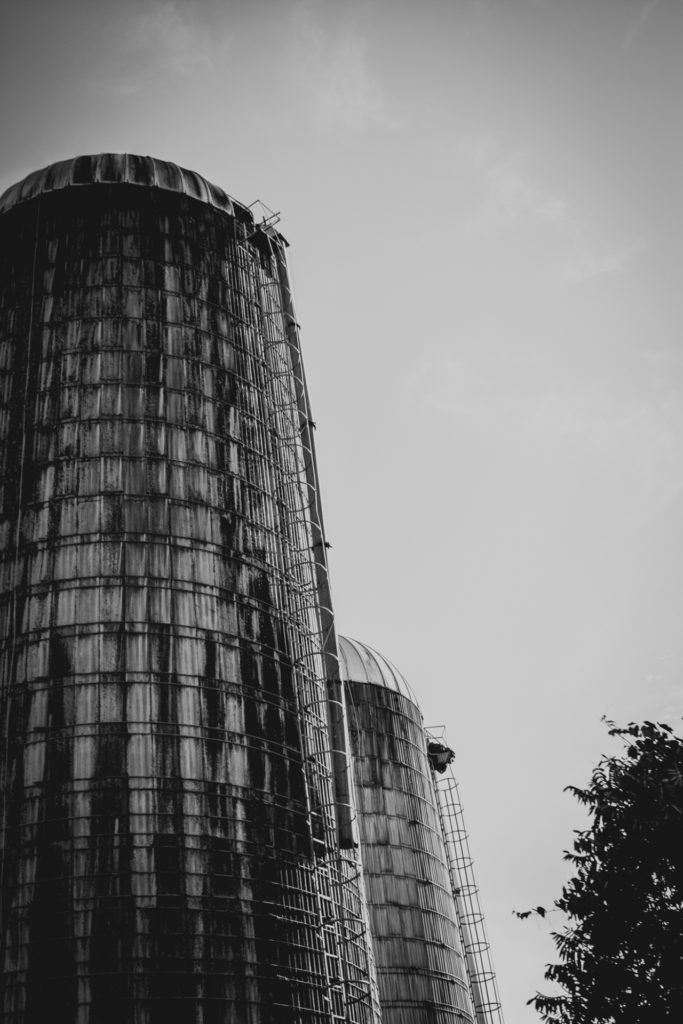 black and white image of two silos on a farm in vermont, photographed by jamie bannon photography.