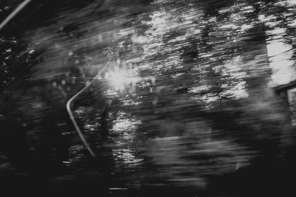 black and white image of blurred trees through a car window, photographed by jamie bannon photography.