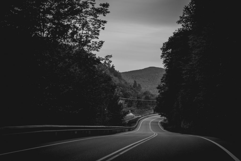 black and white image of a road winding through the mountains in vermont, photographed by jamie bannon photography.