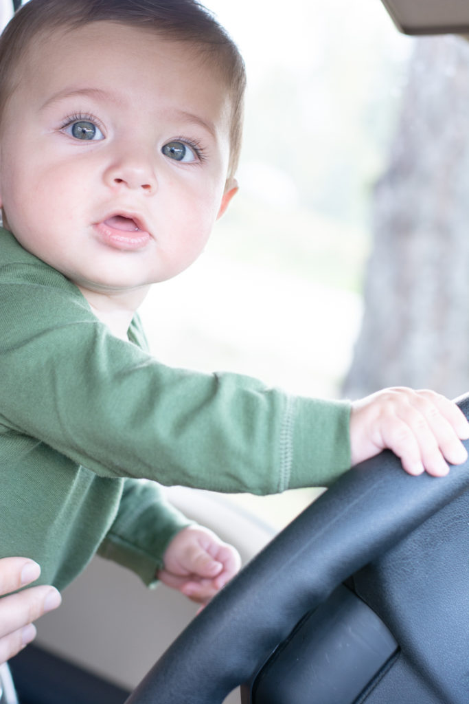 baby pretending to drive a car, photographed by jamie bannon photography.