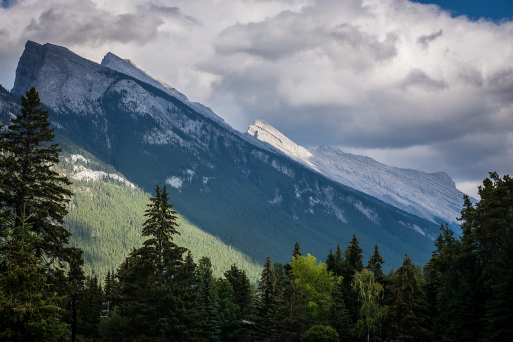 sun shining over mountains in banff, alberta, canada, photographed by jamie bannon photography.