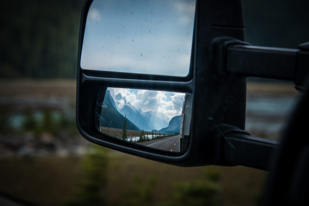 reflection in a side view mirror of the icefields parkway through banff and jasper national parks in alberta, canada, photographed by jamie bannon photography.