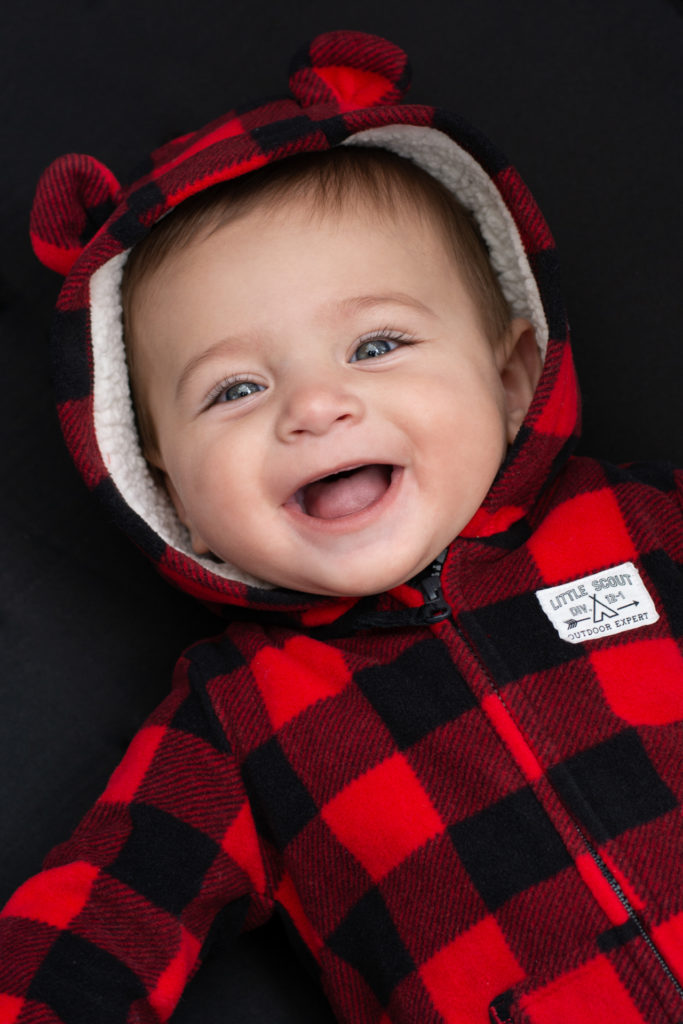 portrait of a smiling baby in a buffalo plaid carter's onesie at a campsite in jasper national park, alberta, canada, photographed by jamie bannon photography.