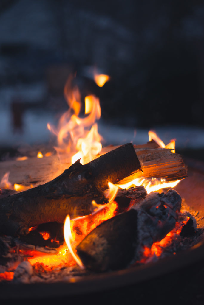 a fire burns at dusk outside on a cold new england winter day, photographed by jamie bannon photography.