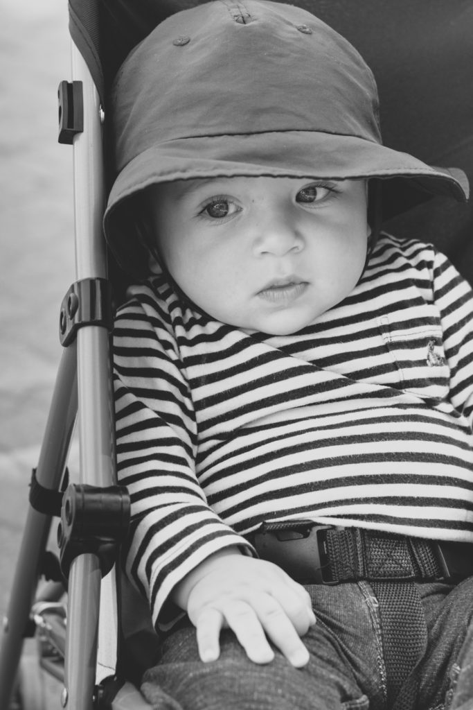 black and white portrait of a baby in his stroller in the town of whistler, british columbia, canada, photographed by jamie bannon photography.