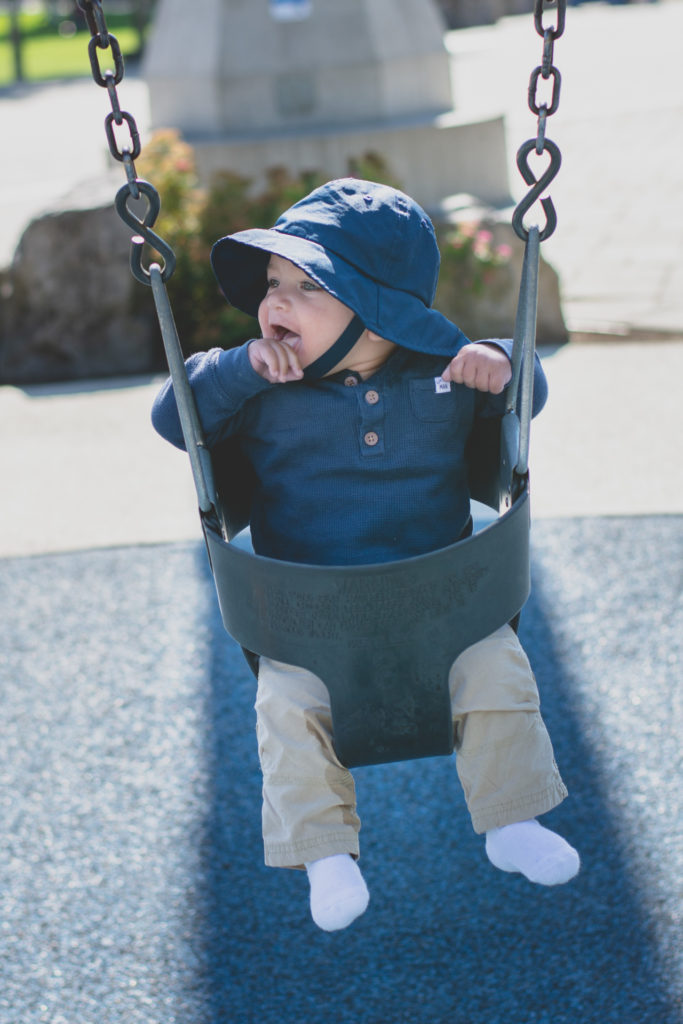 a baby smiles a playground swing in whistler, british columbia, canada, photographed by jamie bannon photography.