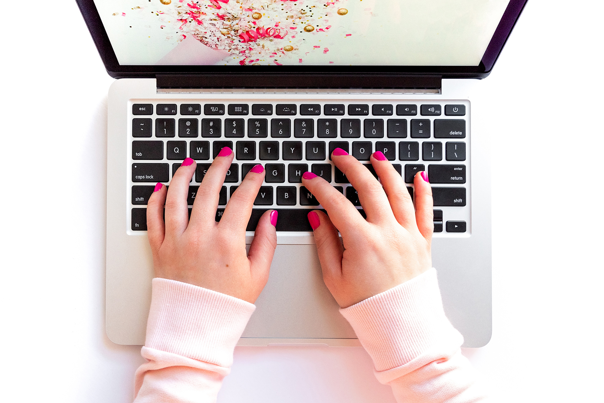 a woman with hot pink painted fingernails types on a laptop, photographed by jamie bannon photography.
