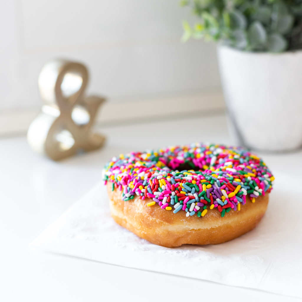 detail of a chocolate frosted doughnut with rainbow sprinkles, as part of a personal branding shoot by jamie bannon photography.