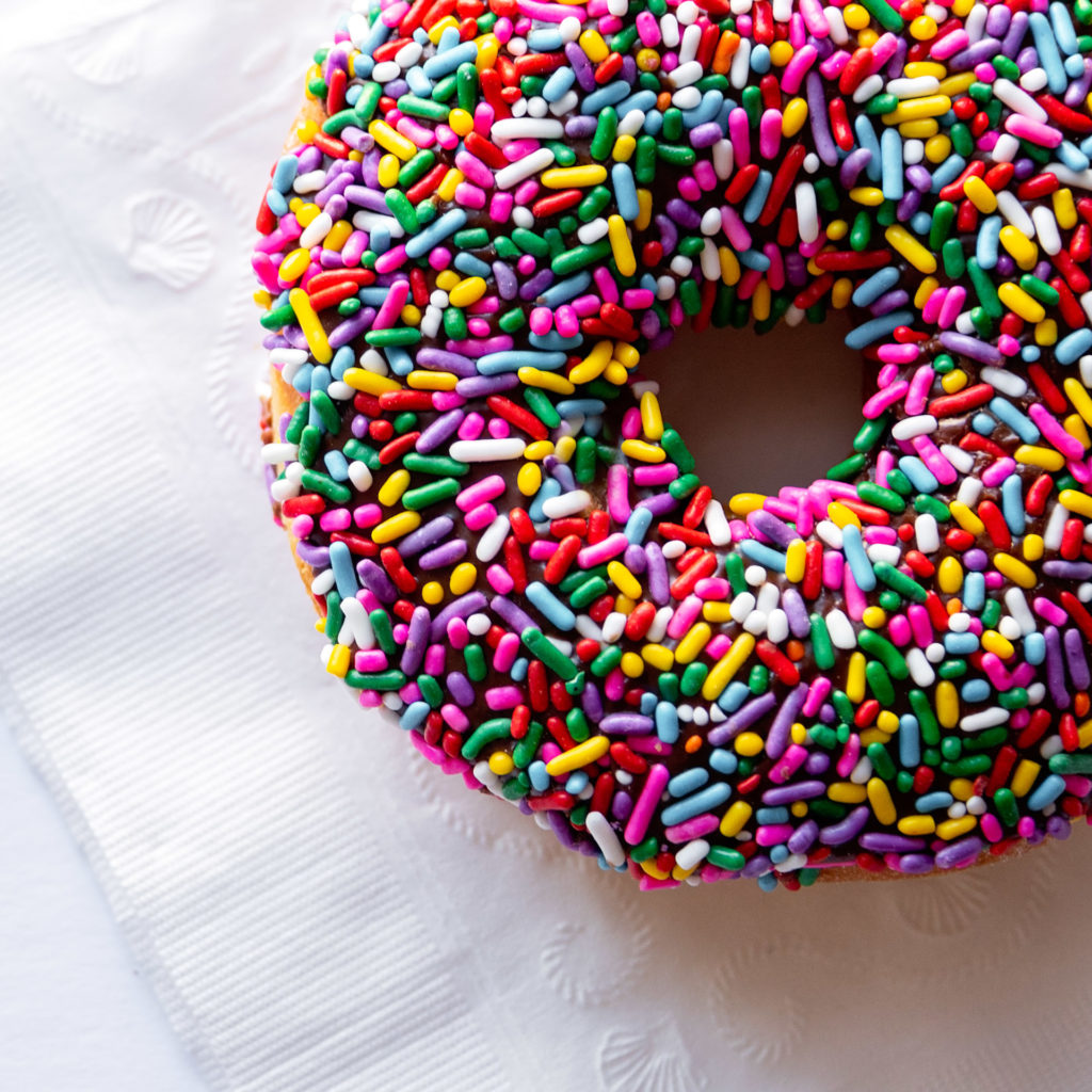 detail of a chocolate frosted doughnut with rainbow sprinkles, as part of a personal branding shoot by jamie bannon photography.