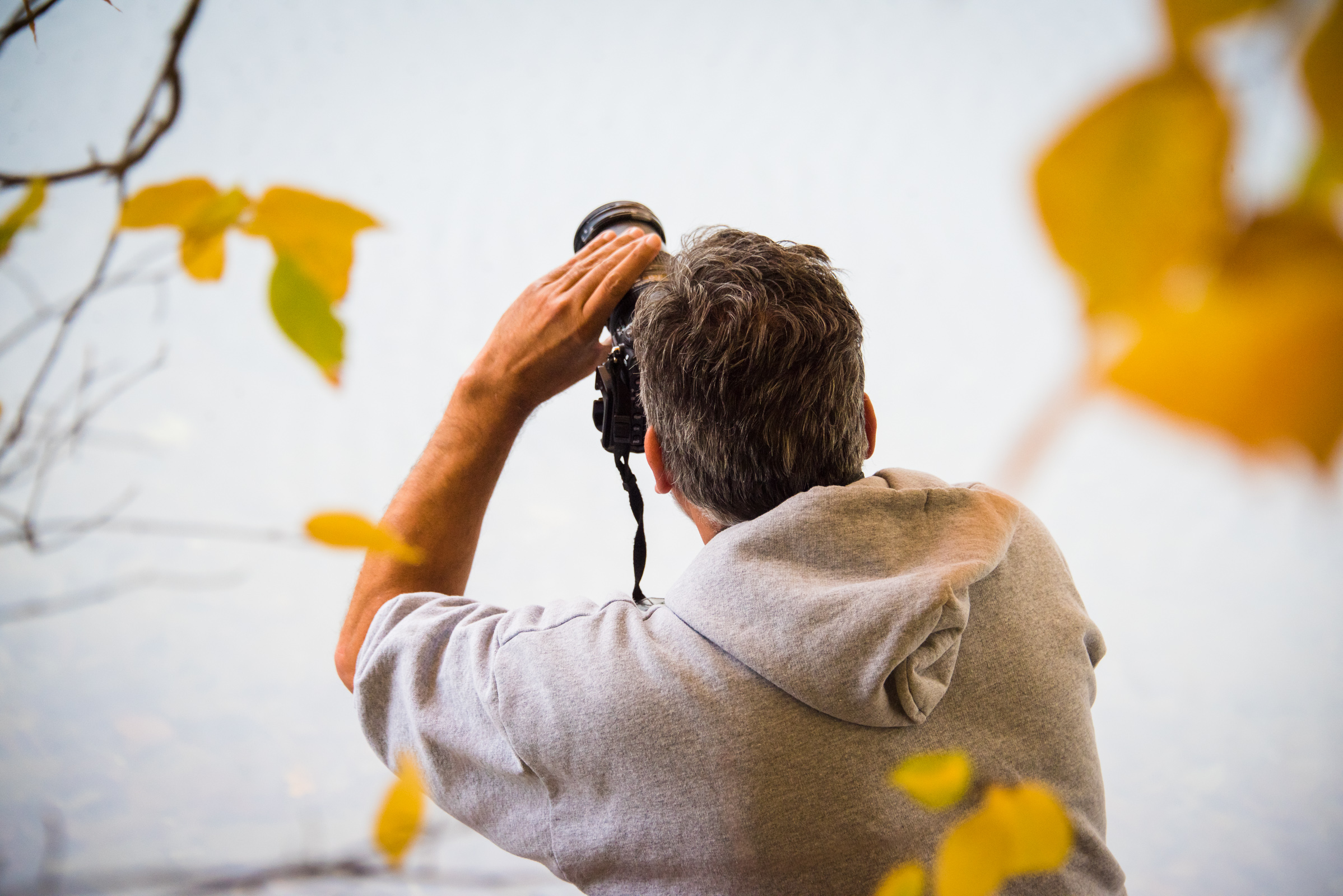 portrait of a photographer shooting a colorful fall landscape by a lake in vermont, photographed by jamie bannon photography.