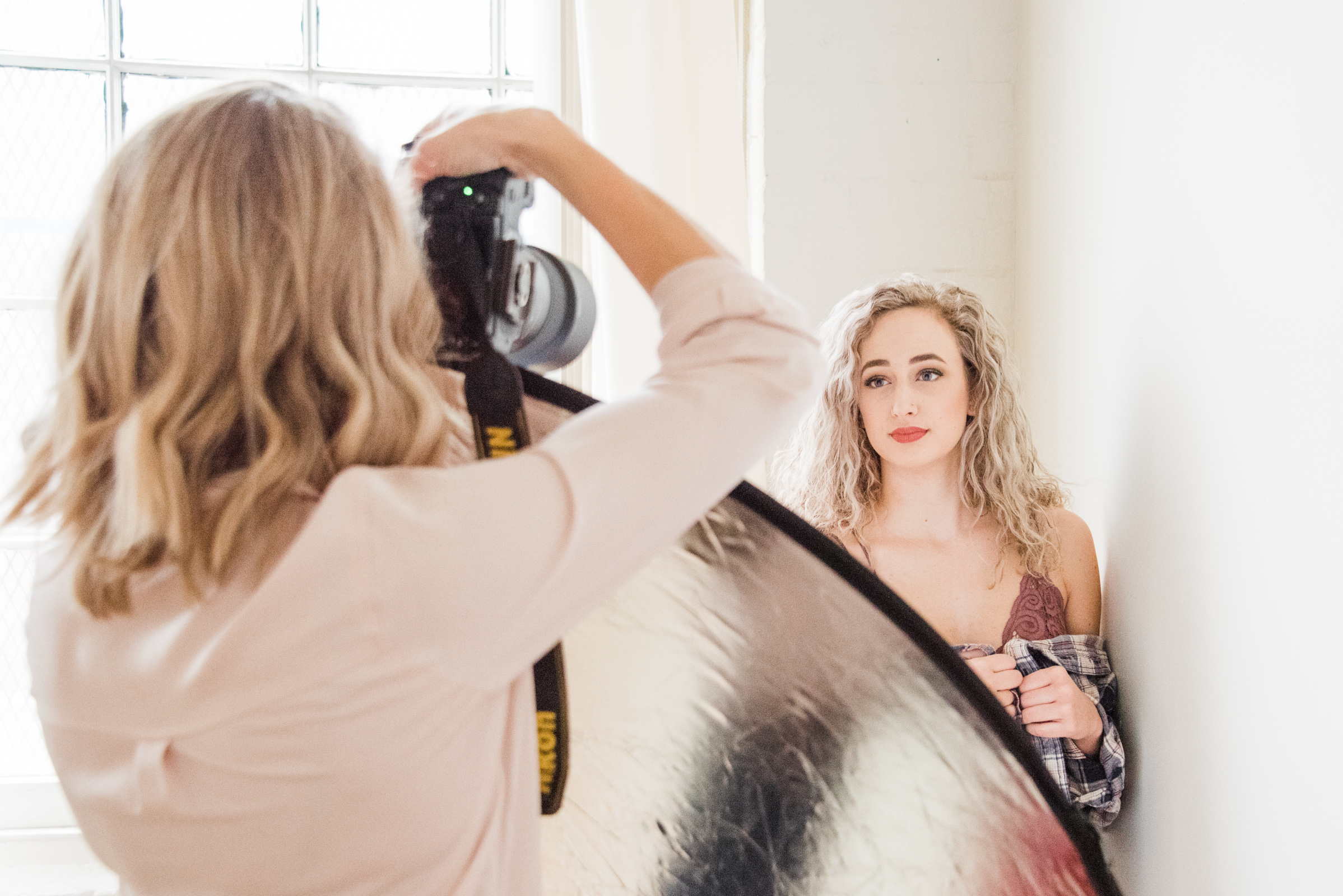 a boudoir photographer photographs her client, photographed as part of a behind the scenes brand shoot by jamie bannon photography.